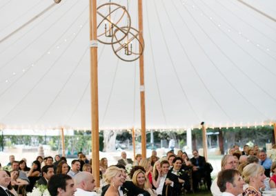 A sailcloth wedding tent with many people inside for a wedding